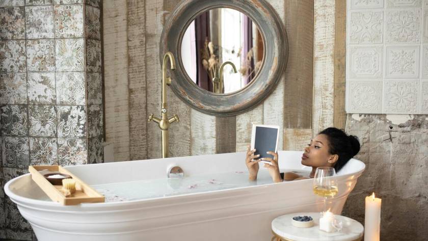 A woman reading a book while on a bathtub