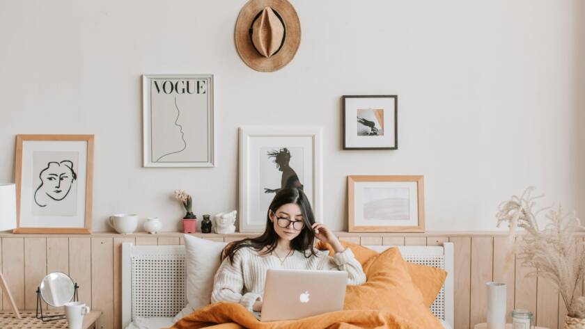 A woman is using a laptop on a bed